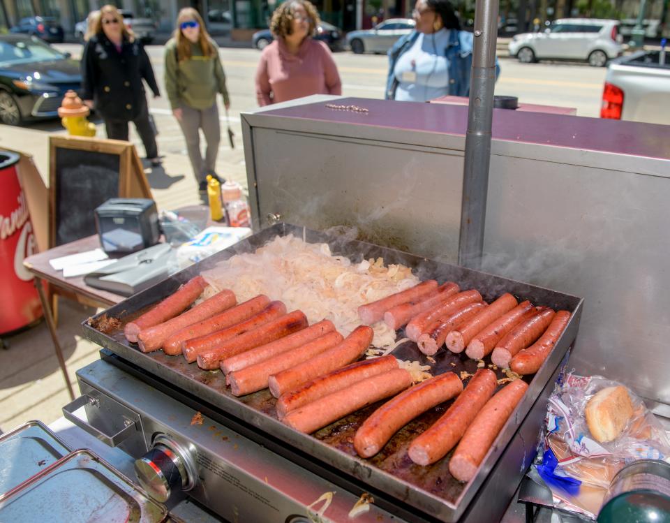 Sausages and onions sizzle on the grill as hungry diners line up for lunch from the Butch's Place food cart in downtown Peoria.