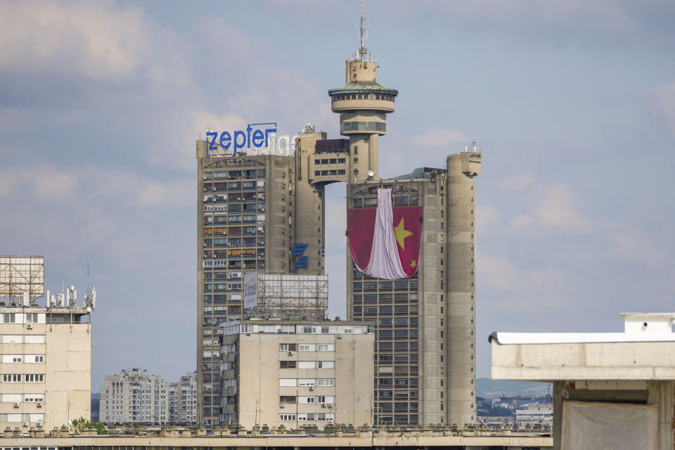 Workers hang on ropes to install a giant Chinese national flag on a skyscraper that is a symbolic gateway leading into the city from the airport, in Belgrade, Serbia, Saturday, May 4, 2024. Chinese leader Xi Jinping's visit to European ally Serbia on Tuesday falls on a symbolic date: the 25th anniversary of the bombing of the Chinese Embassy in Belgrade during NATO's air war over Kosovo. (AP Photo/Darko Vojinovic)