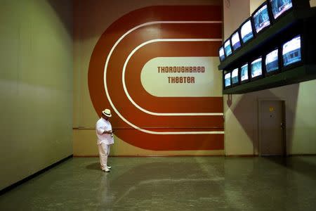 FILE PHOTO - A race-goer checks his phone under a bank of televisions showing horse races for betters before the 138th running of the Preakness Stakes at Pimlico Race Course in Baltimore, Maryland, May 18, 2013. REUTERS/Jonathan Ernst/File Photo