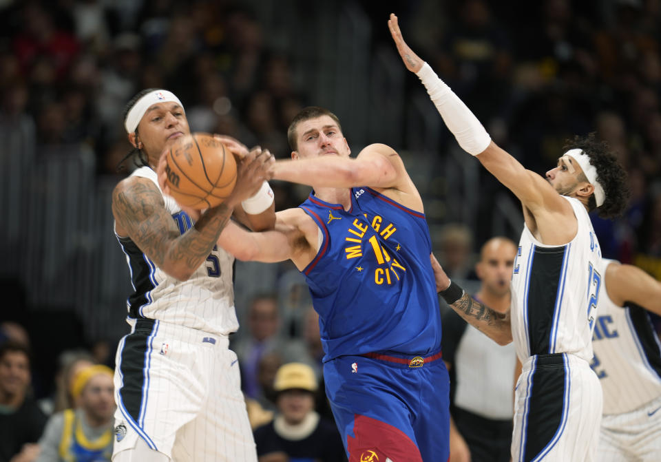 Denver Nuggets center Nikola Jokic, center, loses control of the ball to Orlando Magic forward Paolo Banchero, left, as Magic guard Trevelin Queen defends in the first half of an NBA basketball game Friday, Jan. 5, 2024, in Denver. (AP Photo/David Zalubowski)