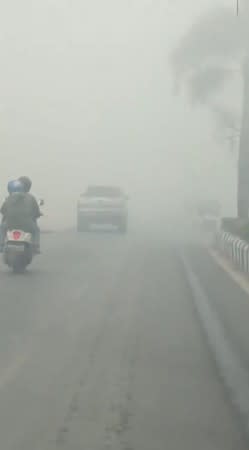 Vehicles move slowly along a smog-covered road during the haze in Sampit