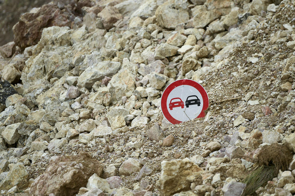 A traffic sign pokes out from the debris of a landslide triggered by Saturday's 7.2 magnitude earthquake, alongside a road in Rampe, Haiti, Wednesday, Aug. 18, 2021. (AP Photo/Matias Delacroix)