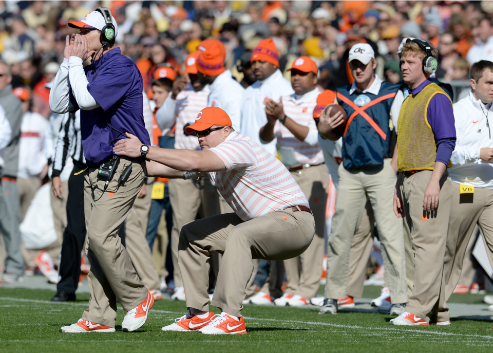 Clemson defensive coordinator Brent Venables is held back by assistant strength coach Adam Smotherman as he steps onto the field of play.