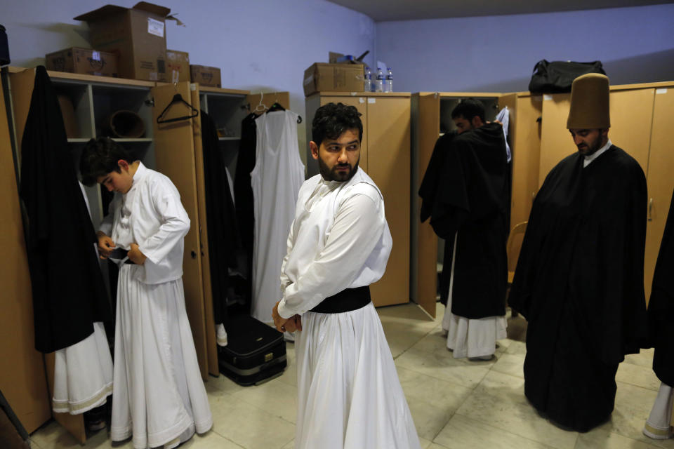 In this photo taken on Sunday, Dec. 16, 2018, whirling dervishes of the Mevlevi order get dressed in the locker room prior to a Sheb-i Arus ceremony in Konya, central Turkey. Every December the Anatolian city hosts a series of events to commemorate the death of 13th century Islamic scholar, poet and Sufi mystic Jalaladdin Rumi. (AP Photo/Lefteris Pitarakis)