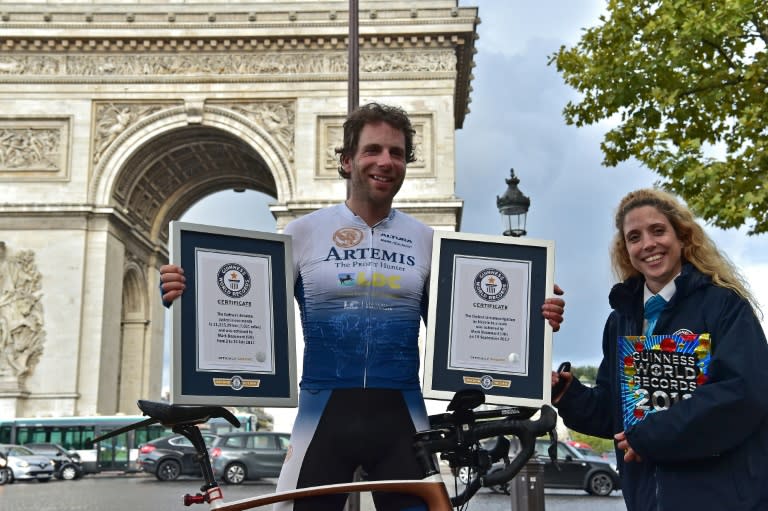 British cyclist Mark Beaumont (C) poses for pictures with Guinness World Records certificates after arriving at the Arc de Triomphe in Paris on September 18, 2017 to complete his tour around the world in 78 days