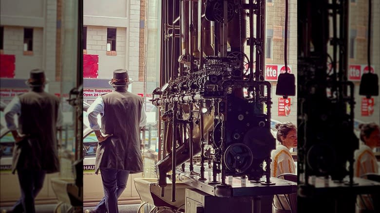 Steampunk waiter stands beside machinery