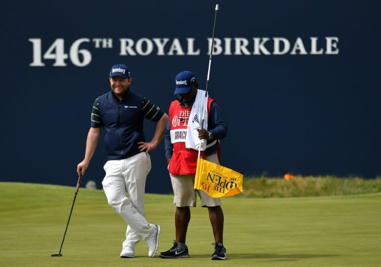 South Africa's Branden Grace (L) waits with his caddie Zack Rasego before holing out on the 18th green during his third round 62 on day three of the Open Golf Championship at Royal Birkdale golf course July 22, 2017