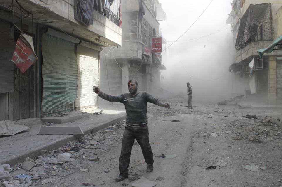 An injured man walks along a street after what activists said was a barrel bomb dropped by forces loyal to Syria's President Bashar al-Assad in Aleppo's al-Myassar neighbourhood