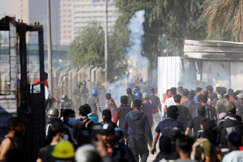 A demonstrator throws tear gas towards Iraqi security forces during the ongoing anti-government protests in Baghdad