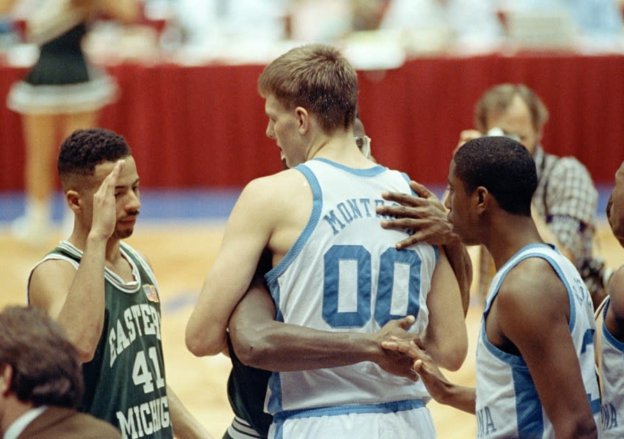 North Carolina’s Eric Montross (00) is embraced by Eastern Michigan’s Marcus Kennedy as Eastern’s Roger Lewis (41) offers his congratulations after the Tarheels 93-67 win in the East Regional semi-final at the Meadowlands in East Rutherford, N.J., March 22, 1991. At right is North Carolina’s Brian Reese. (AP Photo/Charles Rex Arbogast)