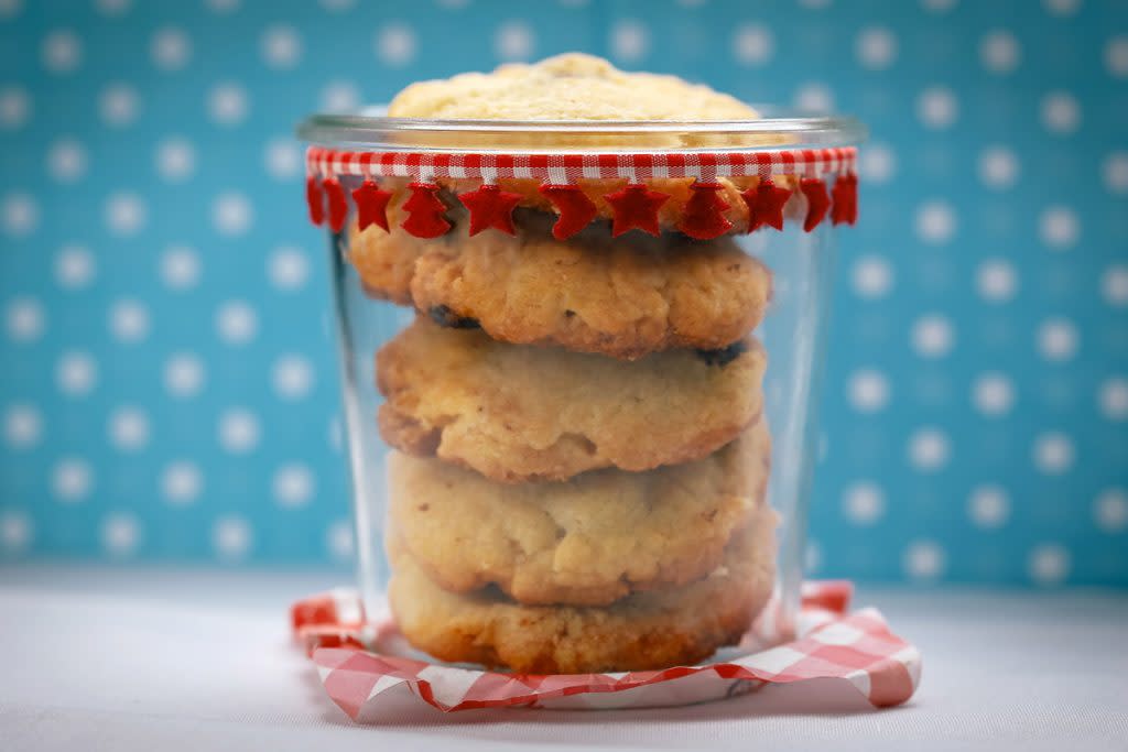 A jar contains cookies against a blue polka dot background. 