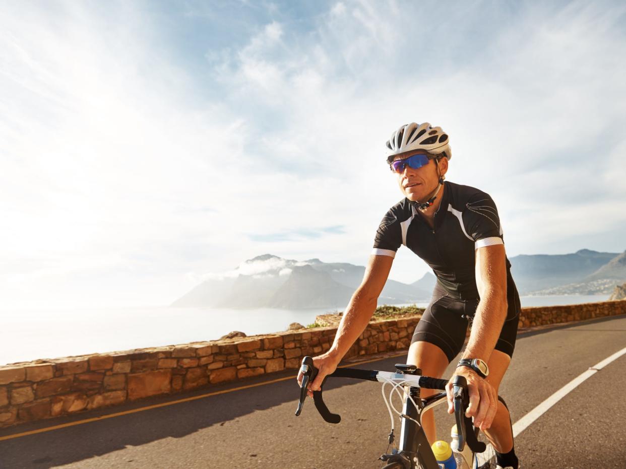 a man in athletic gear riding a bicycle on a road overlooking the coast