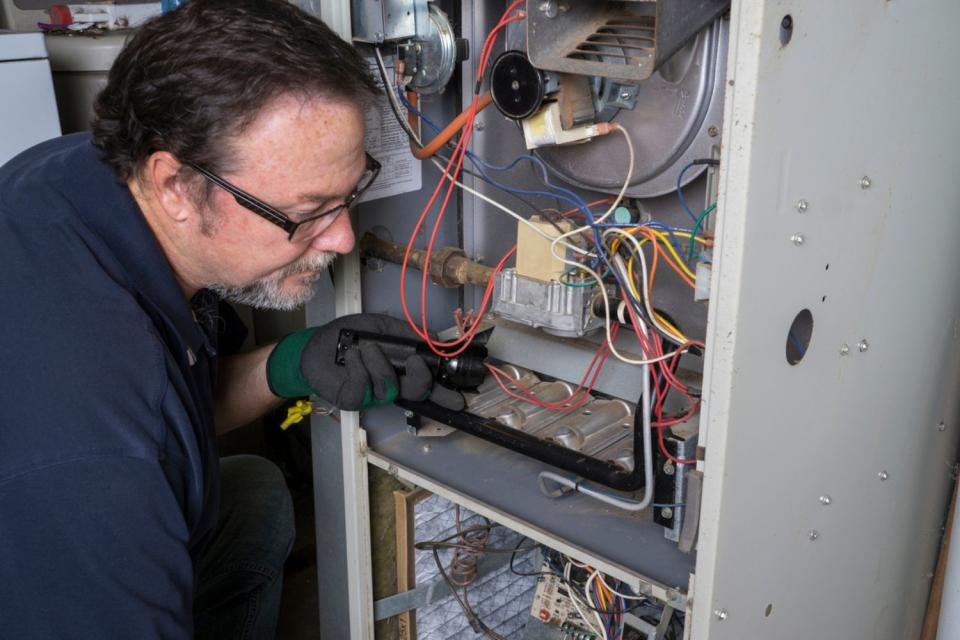 A man examines wiring in a furnace system.