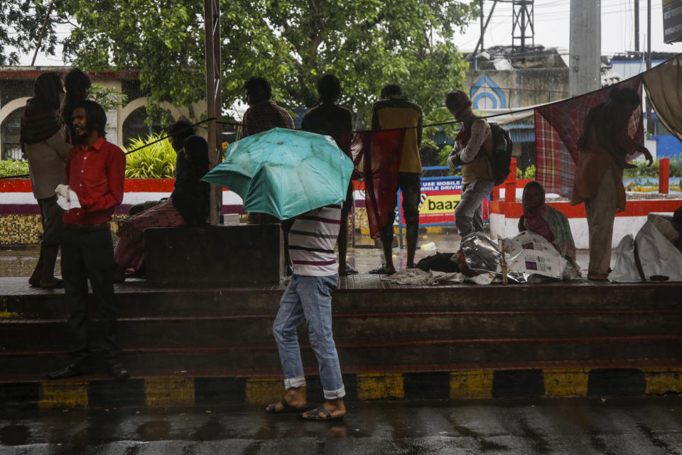 Commuters take shelter in an empty taxi stand at Howrah railway station as it rains in Kolkata, India, Wednesday, May 20, 2020. Amphan, a powerful cyclone has slammed ashore along the coastline of India and Bangladesh where more than 2.6 million people fled to shelters in a frantic evacuation made all the more challenging by the coronavirus pandemic. (AP Photo/Bikas Das)