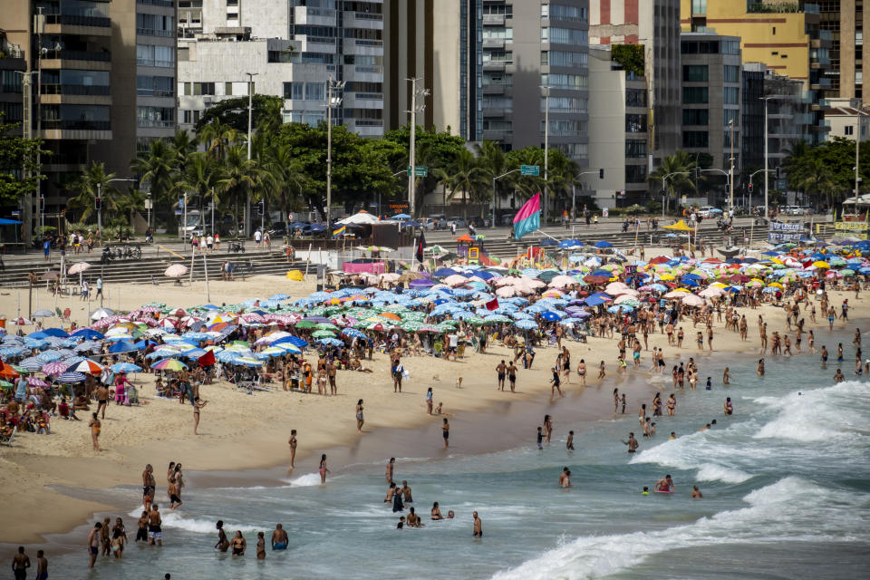 A Brazilian beach lined with people and colorful parasols. 