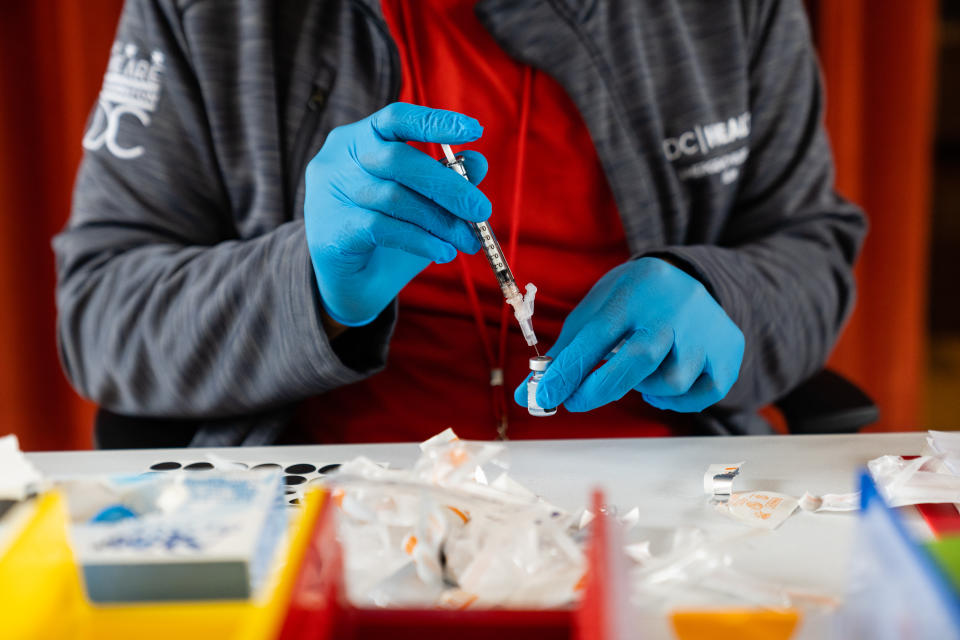 Malik Jaffer, lead nurse, in blue nitrile gloves, prepares a syringe. 