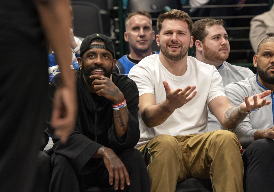 Dallas Mavericks' Luka Doncic, right, argues with a referee, foreground, as Kyrie Irving, left, look on during the second half of an NBA basketball game against the Detroit Pistons, Friday, April 12, 2024, in Dallas. Doncic and Irving were not playing due to injuries. (AP Photo/Jeffrey McWhorter)