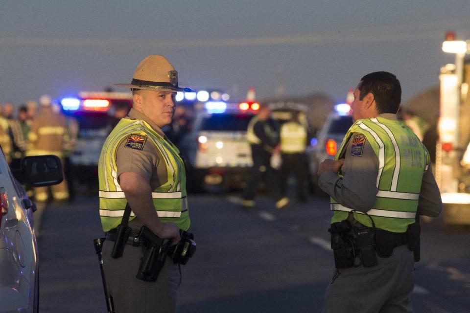 Emergency personnel gather at the scene where an Arizona Department of Public Safety trooper was shot, Thursday, Jan. 12, 2017, at the scene of a rollover accident on Interstate 10 near Tonopah, Ariz. An Arizona state trooper stopped to help at a car wreck along the remote highway Thursday when he was shot and wounded in an ambush by a man who was bashing the officer's head against the pavement until a passing driver shot him to death, authorities said. The trooper suffered a severe wound to his shoulder and upper chest but he is expected to recover at a hospital. (Mark Henle/The Arizona Republic via AP)