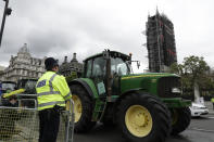 Farmers from the group Save British Farming drive tractors around Parliament Square, backdropped by the Houses of Parliament and the scaffolded Big Ben tower in London, in a protest against cheaply produced lower standard food being imported from the U.S. after Brexit that will undercut them, Wednesday, July 8, 2020. (AP Photo/Matt Dunham)