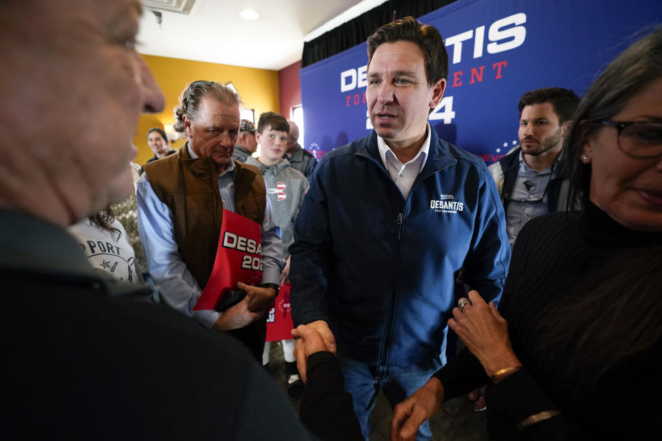 ARCHIVO - Ron DeSantis, gobernador de Florida y aspirante a la candidatura republicana para la presidencia, centro, conversa con partidarios en un acto de campaña, el viernes 3 de noviembre de 2023, en Denison, Iowa. (AP Foto/Charlie Neibergall, archivo)