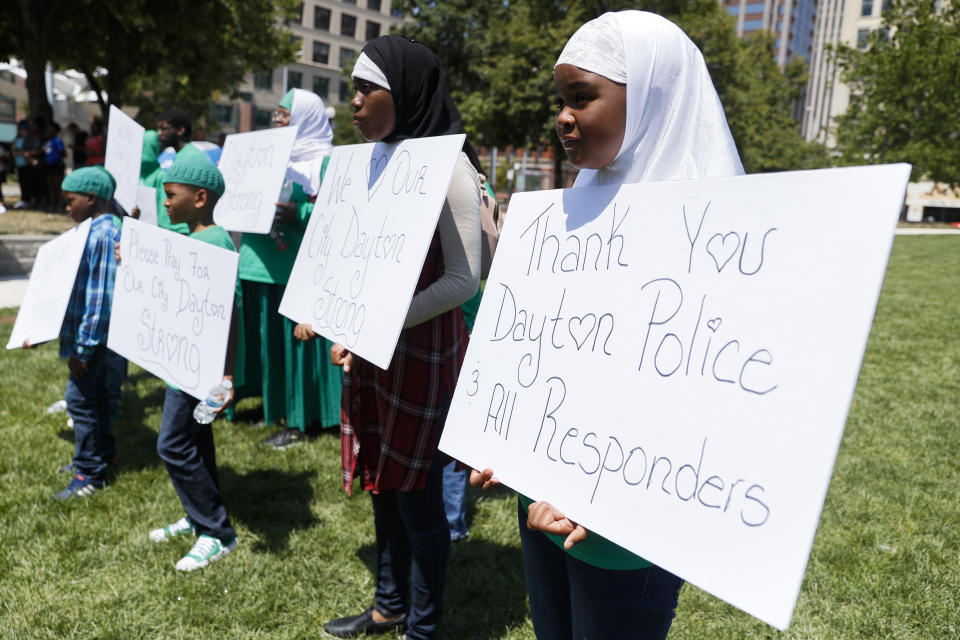 Photo shows mourners holding signs saying "Thank you Dayton Police and all responders" at a vigil for the victims of the Dayton mass shooting.