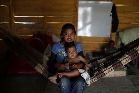 A Venezuelan indigenous girl of Pemon tribe holds a baby as they rest on a hammock in the Brazilian indigenous village Tarau Paru in the border city of Pacaraima, Brazil April 14, 2019. Picture taken April 14, 2019. REUTERS/Pilar Olivares