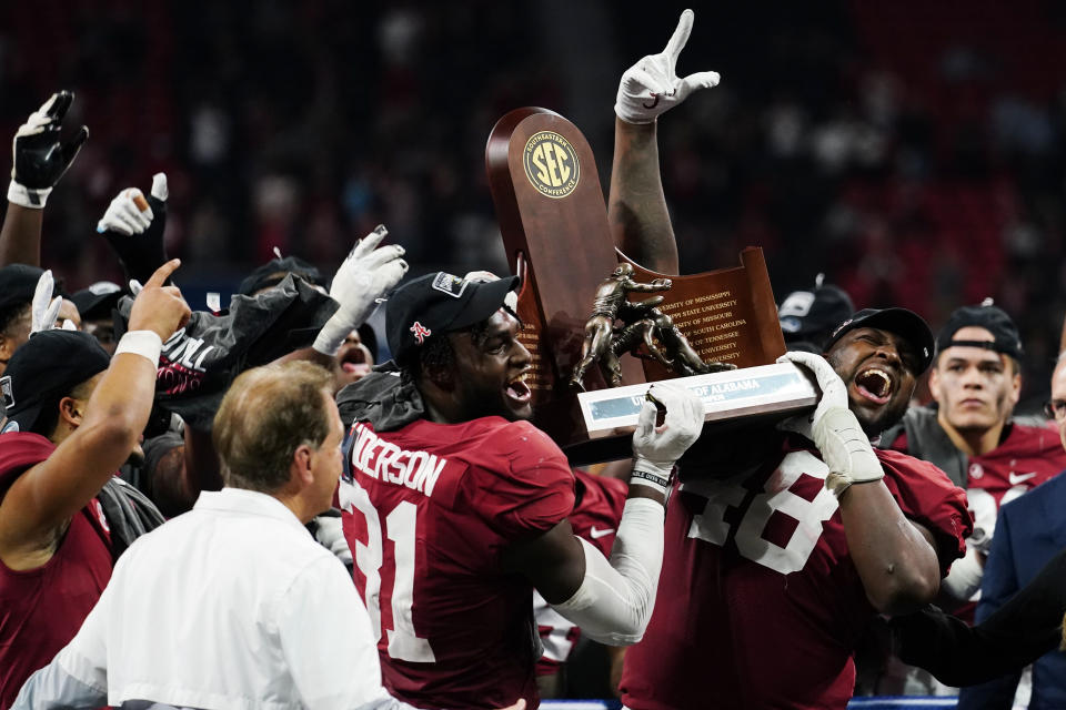 Alabama linebacker Will Anderson Jr. (31) and Alabama defensive lineman Phidarian Mathis (48) hold the Championship trophey after the Southeastern Conference championship NCAA college football game between Georgia and Alabama, Saturday, Dec. 4, 2021, in Atlanta. Alabama won 41-24. (AP Photo/John Bazemore)