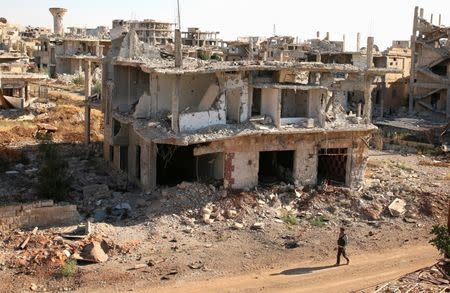 FILE PHOTO: A rebel fighter walks past damaged buildings in a rebel-held part of the southern city of Deraa, Syria June 22, 2017. REUTERS/Alaa Al-Faqir/File Photo