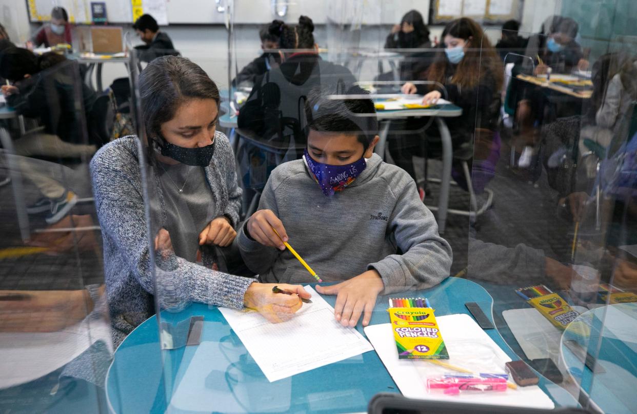 Behind clear partitions for COVID-19 concerns, sixth grade teacher Emily Reverman helps student, Charlie Rojo, 12, with math at Gateway Elementary School in Phoenix on March 18, 2021. Other than a brief return to in-person school in the fall, this was the first day the sixth graders were back in-person at the school since the COVID-19 pandemic began in March 2020.