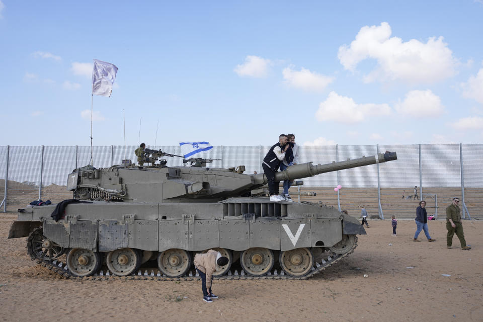 Israelis stand on tanks during an event for families of reservists outside a military base in southern Israel, Tuesday, Feb. 27, 2024. Israel has called up tens of thousands of reservists for its war in Gaza, separating the soldiers from their families for weeks at a time. (AP Photo/Ohad Zwigenberg)