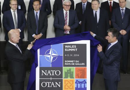 Britain's Foreign Secretary William Hague (L) and NATO Secretary General Anders Fogh Rasmussen (R) unveil the plaque of the next NATO summit in Wales during a NATO foreign ministers meeting at the Alliance headquarters in Brussels June 25, 2014. REUTERS/Francois Lenoir