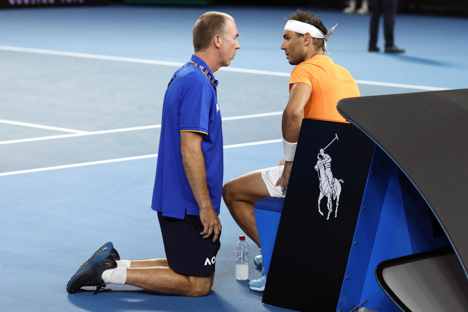 Rafael Nadal, right, of Spain talks with medical staff during his second round match against Mackenzie McDonald of the U.S., at the Australian Open tennis championship in Melbourne, Australia, Wednesday, Jan. 18, 2023. (AP Photo/Asanka Brendon Ratnayake)