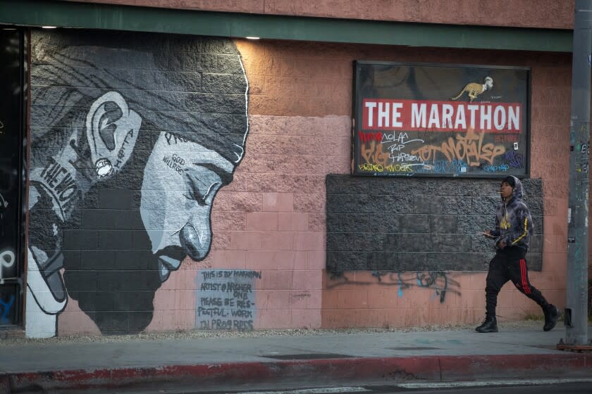 LOS ANGELES, CALIF. -- THURSDAY, JULY 18, 2019: A man walks by a mural at the strip mall property owned by Nipsey Hussle, and where he was killed in South Los Angeles, which has seen a steady flow of tourists and heightened police presence in light of recent trouble and gang presence. The strip mall includes HussleÕs Marathon Clothing store, as well as other businesses. Photo taken in Los Angeles, Calif., on July 18, 2019. (Allen J. Schaben / Los Angeles Times)