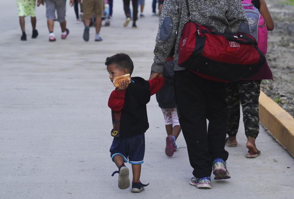 Kevin Bonilla, a 5-year-old Honduran, holds a hotdog as he walks with his family as part of a migrant group leaving Huixtla by foot in Chiapas state, Mexico, early Wednesday, Oct. 27, 2021, continuing a trek north toward Mexico's northern states and the U.S. border. (AP Photo/Marco Ugarte)