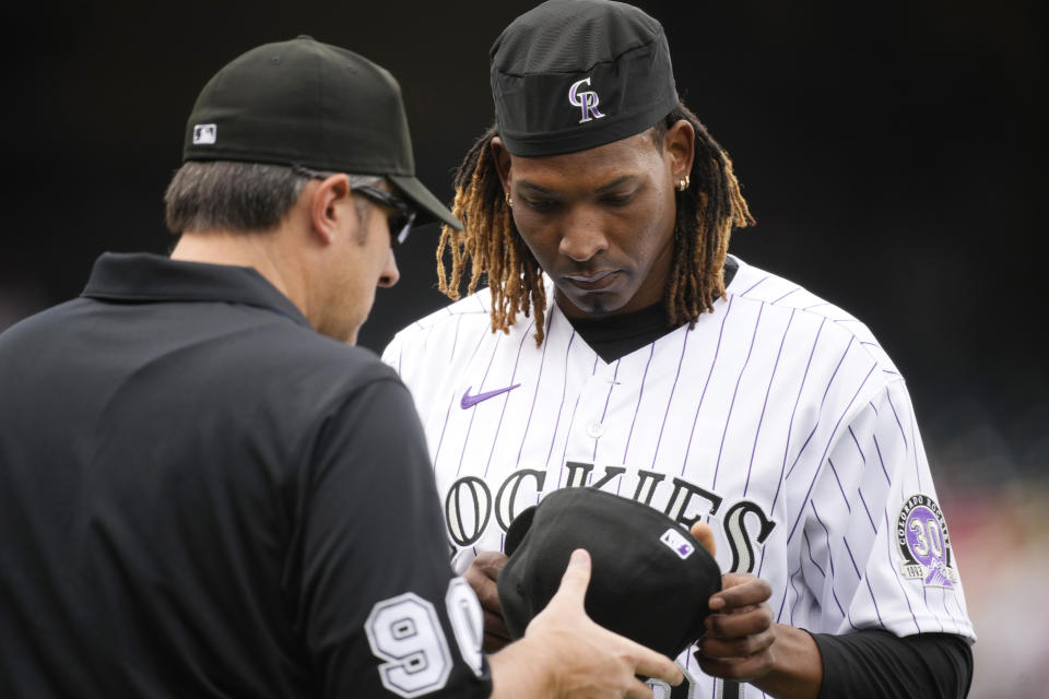 First base umpire Mark Ripperger, left, checks the cap of Colorado Rockies starting pitcher Jose Urena after the top of the second inning of the team's baseball game against the St. Louis Cardinals, Wednesday, April 12, 2023, in Denver. The advent of the pitch clock in major league games this season has all but eliminated any talk between players and umpires. (AP Photo/David Zalubowski)