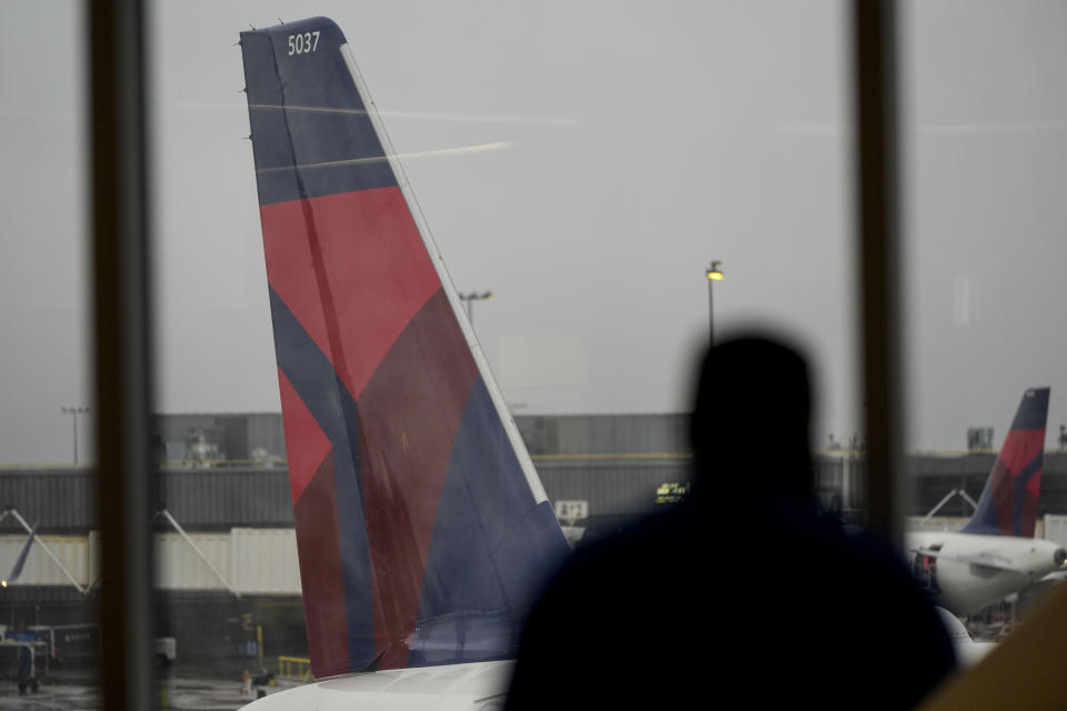 FILE - A man looks out a window at a Delta Airlines plane at Hartsfield-Jackson Atlanta International Airport, Jan. 27, 2024, in Atlanta. On Thursday, July 11, 2024, Delta Air Lines said its second-quarter profit is down 29% from a year earlier, and it's giving a disappointing outlook for the third quarter. (AP Photo/Mike Stewart, File)