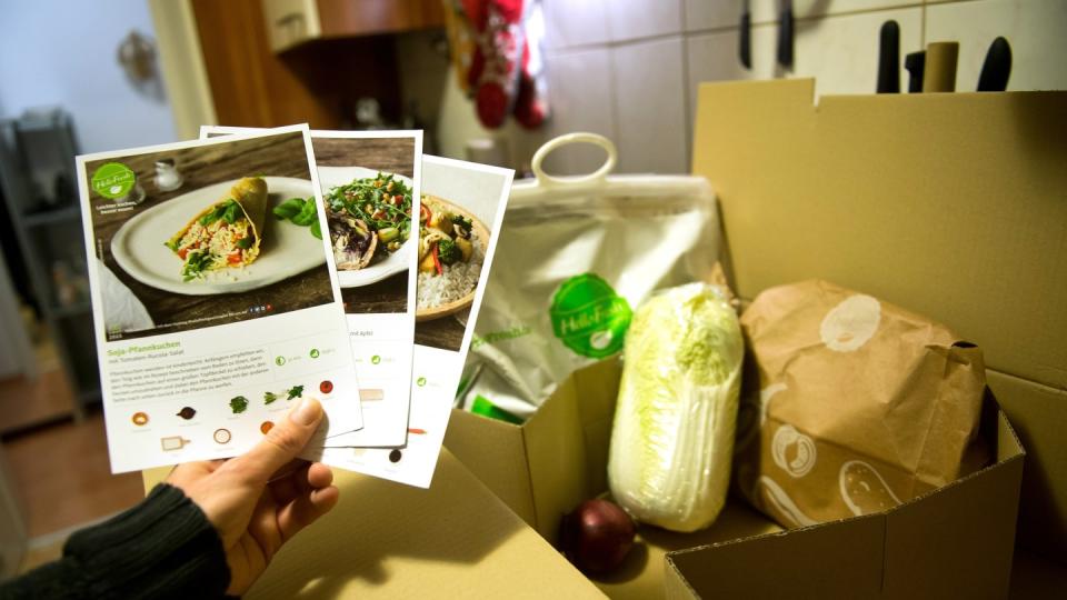 Ein Mann hält mitgelieferte Kochrezepte aus einer HelloFresh Kochbox in der Hand.