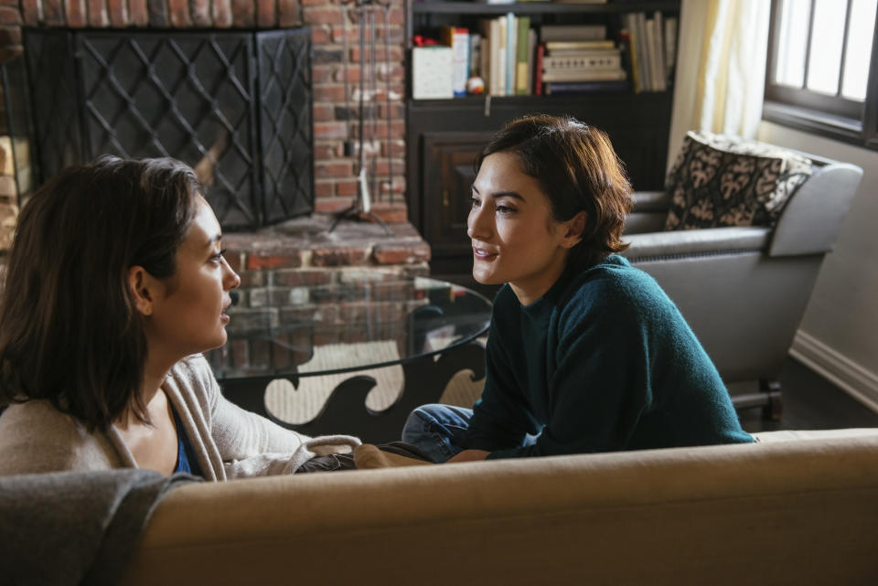 Two women sitting on a couch facing each other, engaged in a conversation