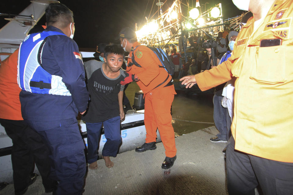 Rescuers assist one of the survivors of a ship collision, center, upon his arrival at a port in Indramayu, West java, Indonesia, Sunday, April 4, 2021. The collision between a cargo ship and a fishing boat left a number of people missing off Indonesia's main island of Java, officials said Sunday. (AP Photo/Panji Wisnu)