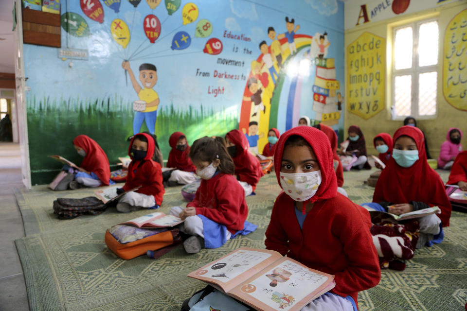 Students wear face masks to protect against the coronavirus at a school, in Peshawar, Pakistan, Monday, Feb. 1, 2021. Pakistani authorities reopened primary and middle schools on Monday and will open universities in the last of a phased reopening due to the pandemic. (AP Photo/Muhammad Sajjad)