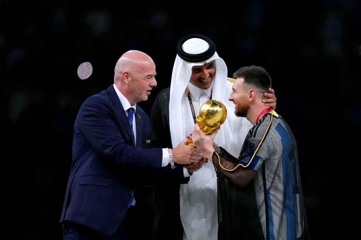 FIFA president Gianni Infantino, left, and The Emir of Qatar, Sheikh Tamim bin Hamad Al Thani, present Argentina captain Lionel Messi with the World Cup trophy (Nick Potts/PA) (PA Wire)