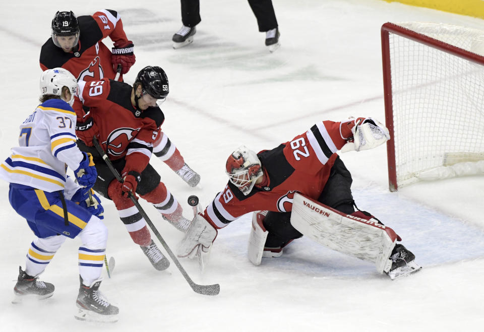 New Jersey Devils goaltender Mackenzie Blackwood (29) deflects the puck as New Jersey Devils center Janne Kuokkanen (59) checks Sabres center Casey Mittelstadt (37) during the first period of an NHL hockey game Tuesday, Feb. 23, 2021, in Newark, N.J. (AP Photo/Bill Kostroun)