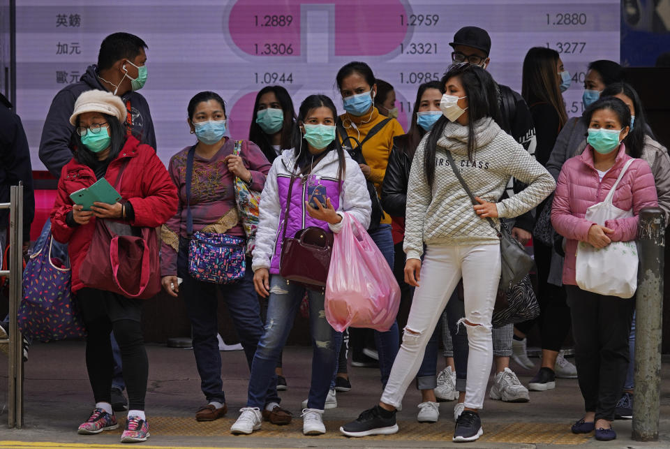 Gente con mascarillas de protección en una esquina en una calle de Hong Kong, el domingo 9 de febrero de 2020. (AP Foto/Vincent Yu)