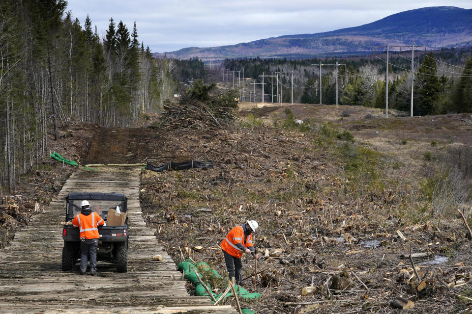 FILE - Workers for Northern Clearing pound stakes to mark land on an existing Central Maine Power power line corridor that has been recently widened to make way for new utility poles, near Bingham, Maine, April 26, 2021. The Maine Department of Environmental Protection announced that construction of a transmission line could resume after state voters opposed the project in an election. (AP Photo/Robert F. Bukaty, File)