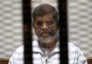 FILE PHOTO - Ousted Egyptian President Mursi is seen behind bars during his trial at a court in Cairo