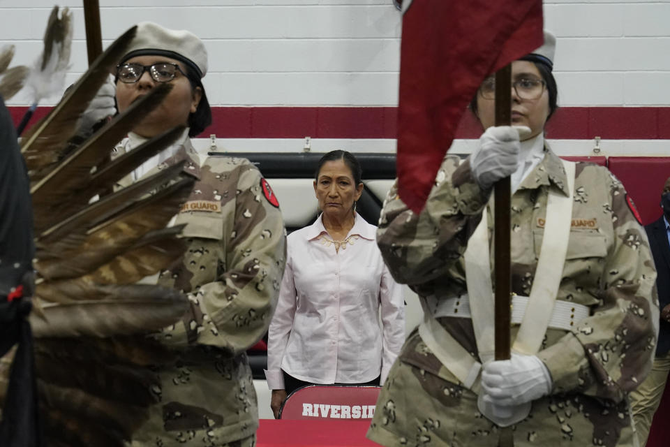 U.S. Secretary of the Interior Deb Haaland stands as the Riverside Indian School color guard presents the colors Saturday, July 9, 2022, in Anadarko, Okla. Native American tribal elders who were once students at government-backed Indian boarding schools testified Saturday about the hardships they endured, including beatings, whippings, sexual assaults, forced haircuts and painful nicknames. (AP Photo/Sue Ogrocki)