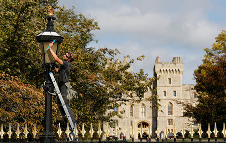 A worker cleans the lanterns at the gates of Windsor Castle a day ahead of the royal wedding between Princess Eugenie and Jack Brooksbank in Windsor, Britain, October 11, 2018. REUTERS/Darren Staples