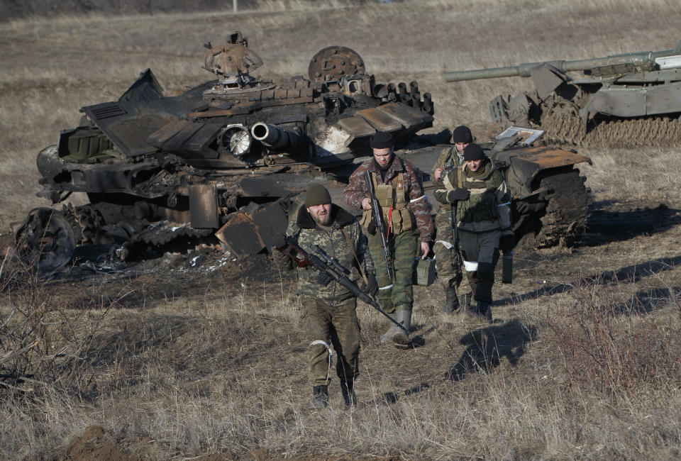 FILE - Russia-backed separatists walk after inspecting destroyed Ukrainian army tanks for functional weapons and ammunition near the village of Lohvynove, outside Debaltseve, Ukraine, Sunday, Feb. 22, 2015, on the edge of the territory under their control. A peace agreement for eastern Ukraine has remained stalled for years, but it has come into the spotlight again amid a Russian military buildup near Ukraine that has fueled invasion fears. On Thursday, Feb. 10, 2022 presidential advisers from Russia, Ukraine, France and Germany are set to meet in Berlin to discuss ways of implementing the deal that was signed in the Belarusian capital of Minsk in 2015. (AP Photo/Vadim Ghirda, File)