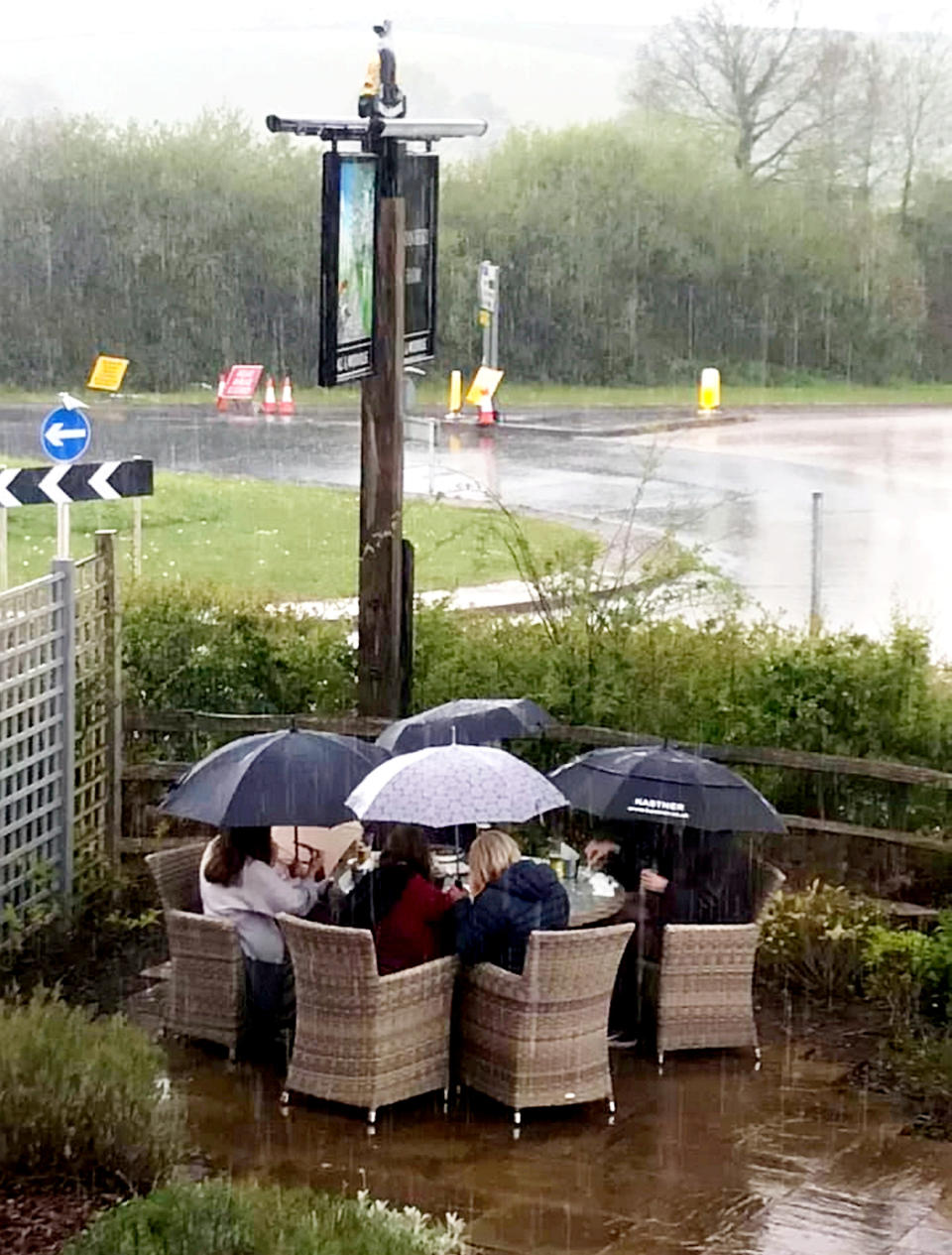 The comical photo showed the family huddled under umbrellas in a beer garden as they tried to enjoy the Bank Holiday. (SWNS)