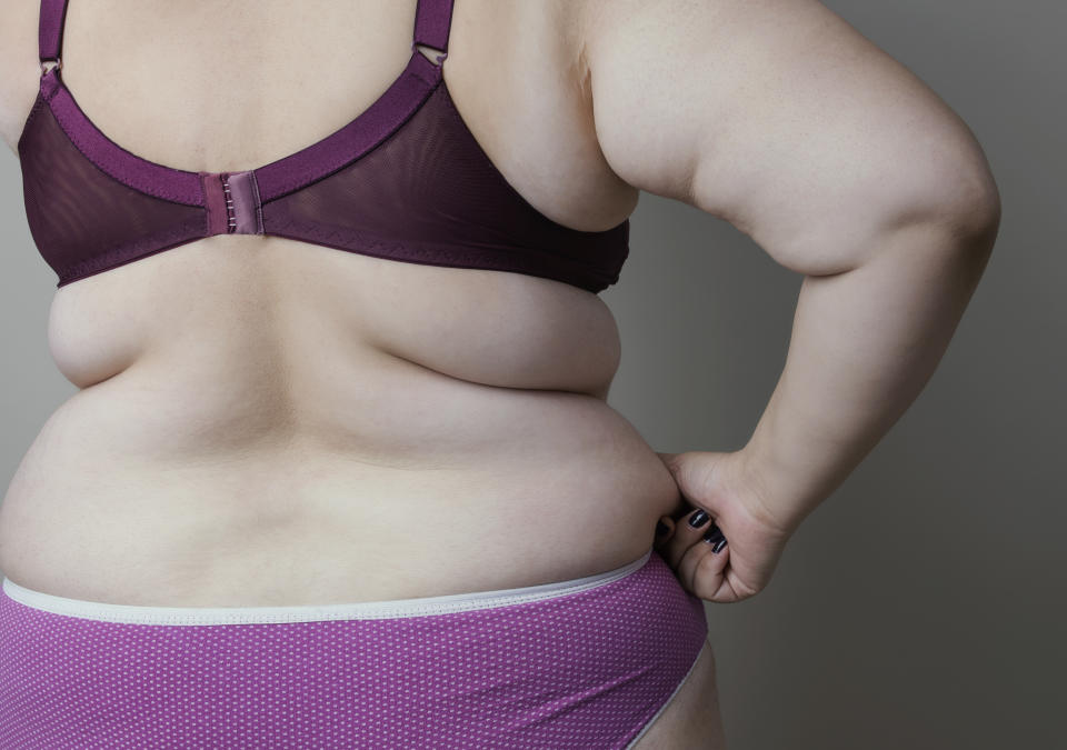 Overweight young woman with fat belly, close up, studio shot